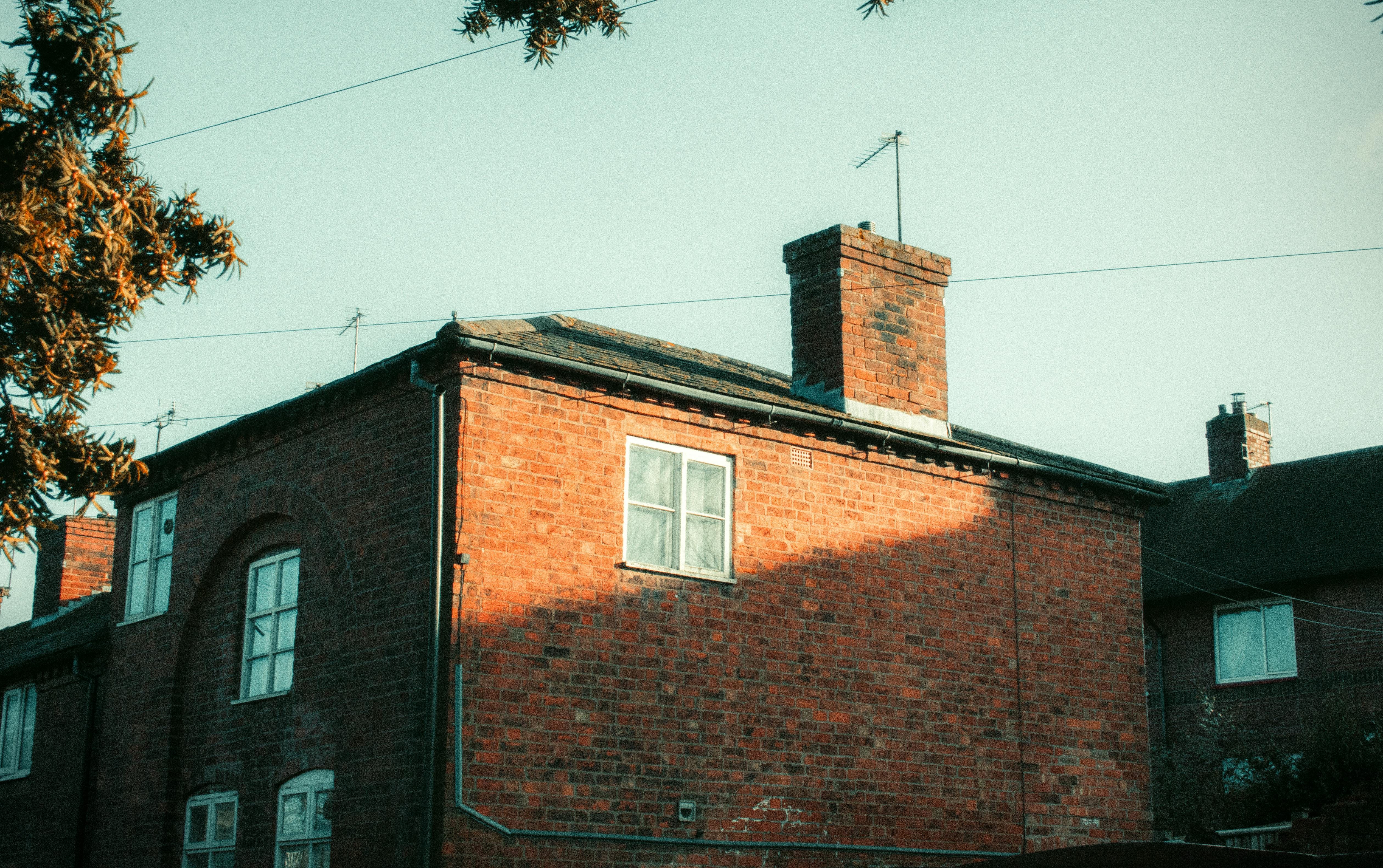 Tall brick chimney stack on the roof of a red brick house in evening light